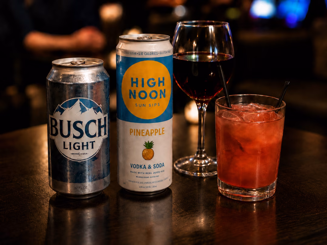 Busch Light, High Noon Pineapple, red wine, and a cocktail on the bar